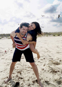 Full length of smiling young woman jumping on beach