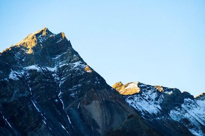 Low angle view of snowcapped mountains against clear sky