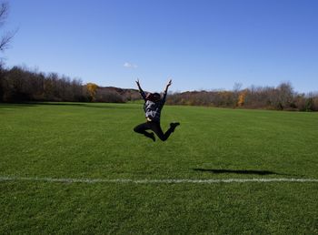 Man jumping on field against clear sky