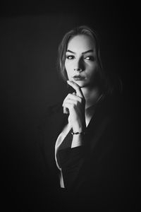 Portrait of beautiful young woman against black background