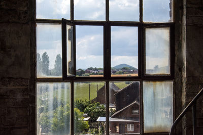 Houses against sky seen through window