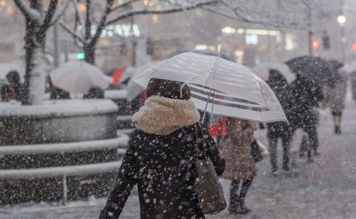 Rear view of woman walking on snow covered road
