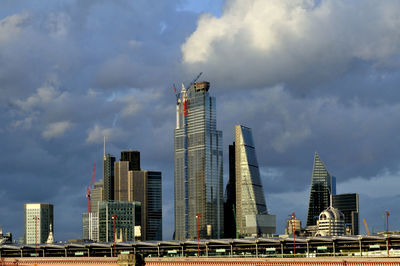 Modern buildings in city against cloudy sky