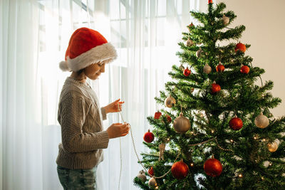 The girl decorates the christmas tree for the holiday. preparing for christmas and new year. 