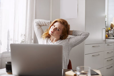 Woman stretching while using laptop