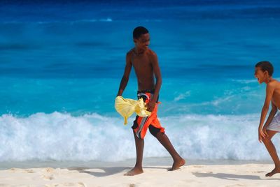 Full length of shirtless man standing on beach