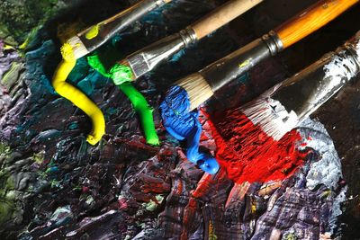 High angle view of paintbrushes on messy palette