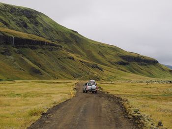 Car on road amidst land against sky