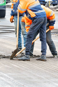 Road workers use shovels to clean the old road surface on the roadway.