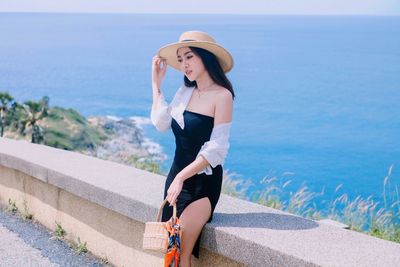 Woman in hat standing against sea