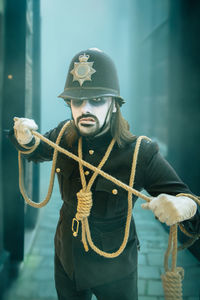 Male cosplayer in a scary british police uniform with hangmans noose in old london town at halloween