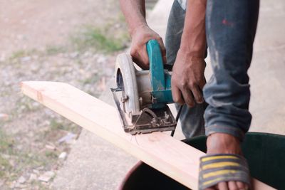 Low section of man cutting wood at workshop