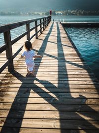 Full length toddler child running on a peer by a lake