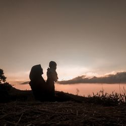 Silhouette people on land against sky during sunset