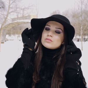 Young woman with eyes closed standing at park during winter