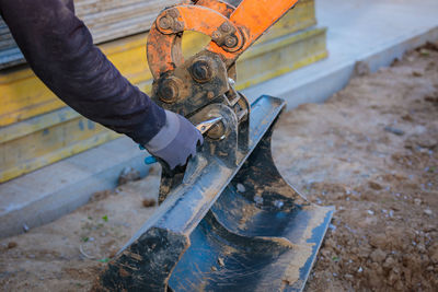 A man repairs a tractor bucket, changes the mounting sleeve. replacing the nozzle on the tractor 