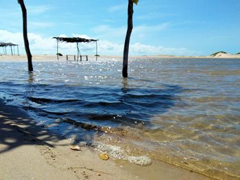 The shadow of a thatched beach hut projected onto the waters of a river