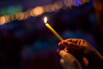 Close-up of hand holding lit candles