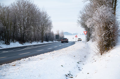 Road snow covered forest, slippery  frosty street winter, empty highway in cold temperature weather 