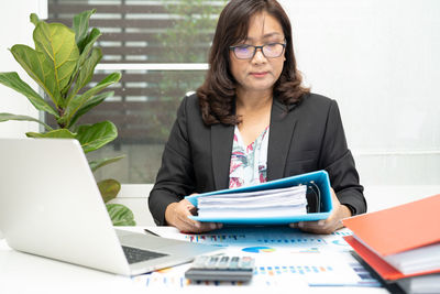 Young businesswoman using laptop while sitting on table