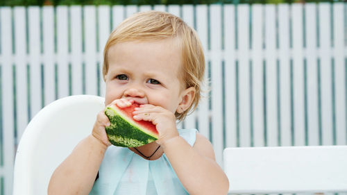 Summer, in the garden, funny one-year-old blond girl eating watermelon