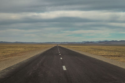 Road passing through landscape against cloudy sky