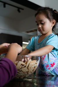 Kids making kek batik or malaysian triple chocolate dessert. crushing the cookies into tiny pieces.