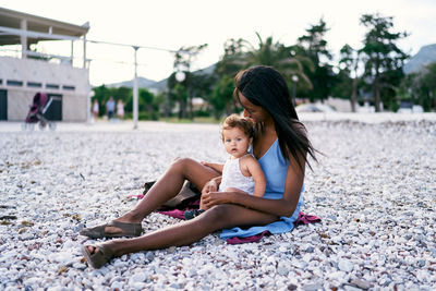 Young woman sitting on pebbles at beach