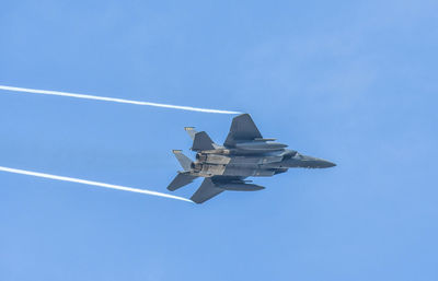 Low angle view of airplane flying against clear blue sky