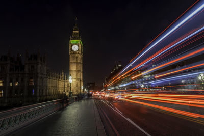 Light trails by big ben in city at night