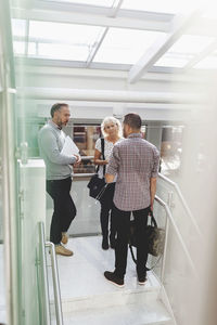 Businesspeople discussing on steps in modern office