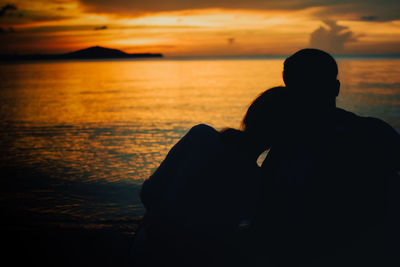 Silhouette men at beach against sky during sunset