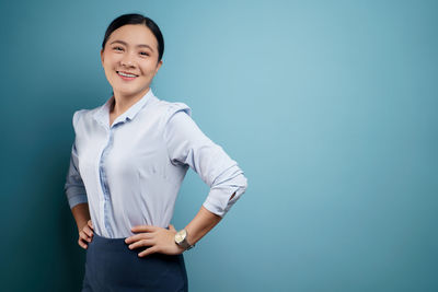 Portrait of a smiling young woman against blue background