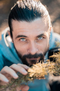 Close-up portrait of young man holding plant