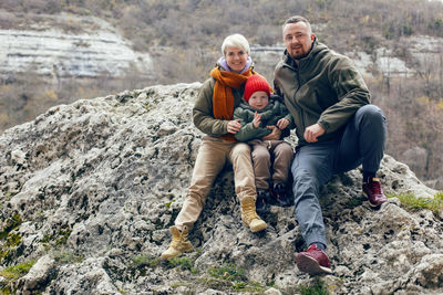 Family with a child sitting on a rock in autumn