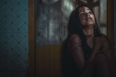 Naked injured woman sitting by wooden door