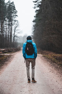 Rear view of man with backpack standing on road