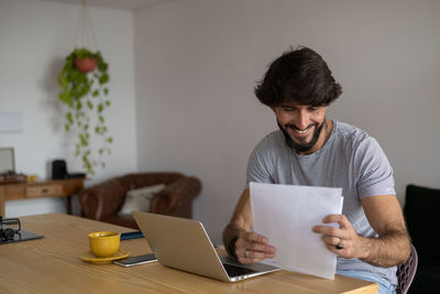 Man working at home in his kitchen with laptop and papers on wooden desk.  notebook . home office