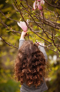 Close-up rear view of a girl plucking flower