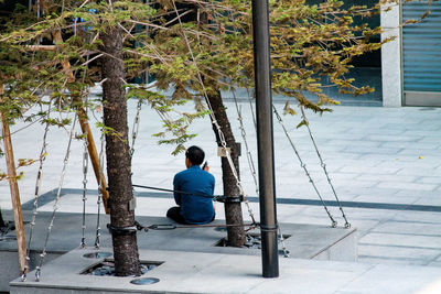 Man sitting beside a tree in the city