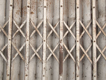 Full frame shot of rusty metal fence against wall