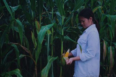 Side view of woman picking corn in farm