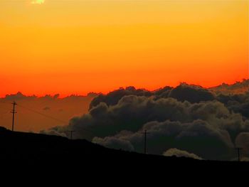 Scenic view of dramatic sky over silhouette landscape during sunset