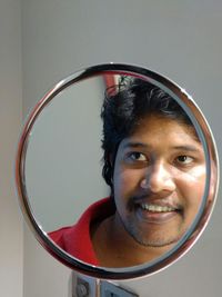 Reflection of smiling man in mirror on wall