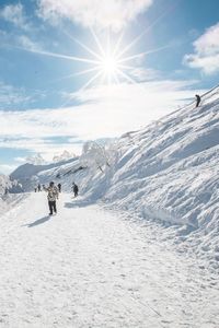 People skiing on snow covered mountain against sky