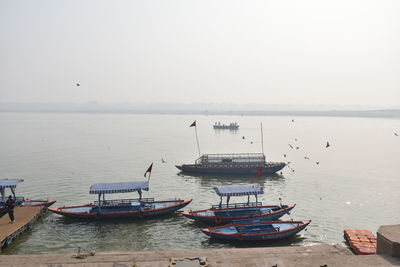 Fishing boats moored in sea against clear sky