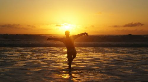Silhouette man standing on beach against sky during sunset