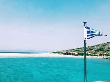 Greek flag in sea against sky