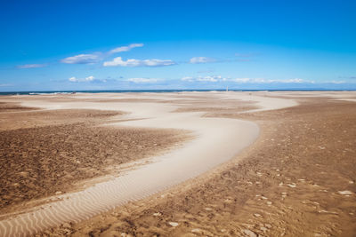 Scenic view of beach and dune against blue sky