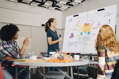 Smiling businesswoman explaining plastic waste management plan to technicians over whiteboard at creative office